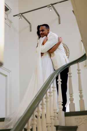 A couple shares an intimate moment on a white staircase during their wedding first look.