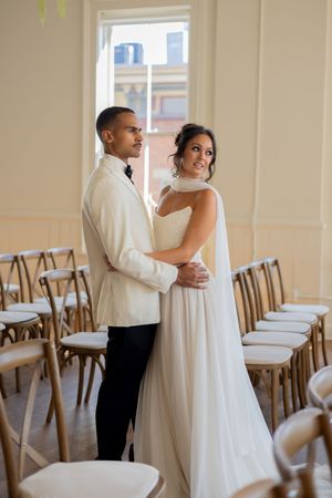 A tender first look moment between a couple in wedding attire in a light-filled room.