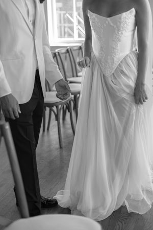 Close-up details of wedding attire showing white dress and formal suit during first look.