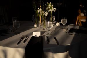 An elegant restaurant table setting with white linens, wine glasses, and soft candlelight creating an intimate ambiance.