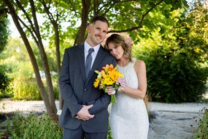 Romantic garden wedding portraits with couple holding bright yellow and pink floral bouquet.
