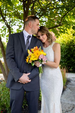 Intimate wedding photography session in garden setting with sunflower bouquet and white lace gown.