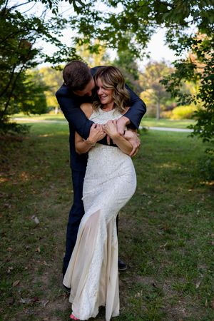 Couple shares passionate dance dip in garden setting during wedding photoshoot.