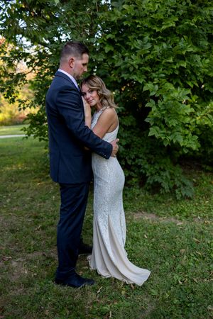 Intimate garden wedding portraits with couple embracing under leafy green canopy.