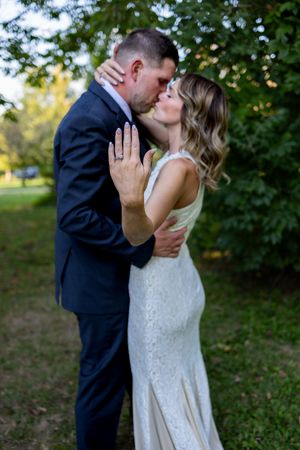 Newlyweds share intimate moment in garden setting with lush greenery.