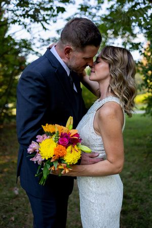 Romantic garden wedding portrait with colorful summer bouquet and intimate embrace.