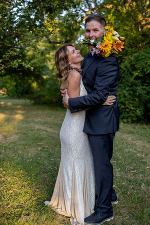 Wedding couple embraces in a natural outdoor setting with autumn foliage.