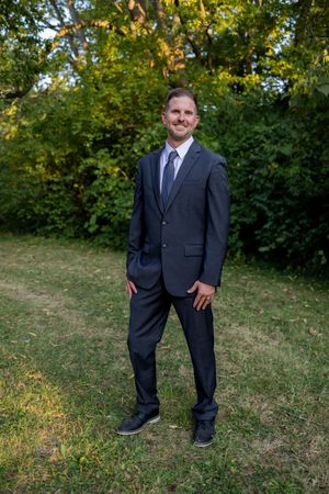 Formal portrait sequence in a navy suit against a green outdoor background.