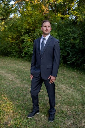 Series of formal portraits showing different poses in a dark suit outdoors.