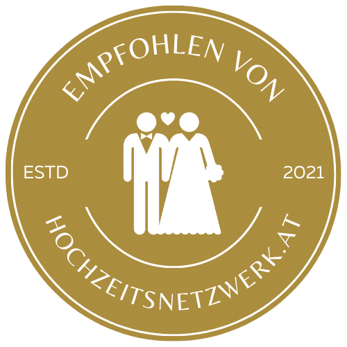 A golden circular badge with wedding couple icon and text 'Empfohlen von Hochzeitsnetzwerk.at' showing establishment in 2021.