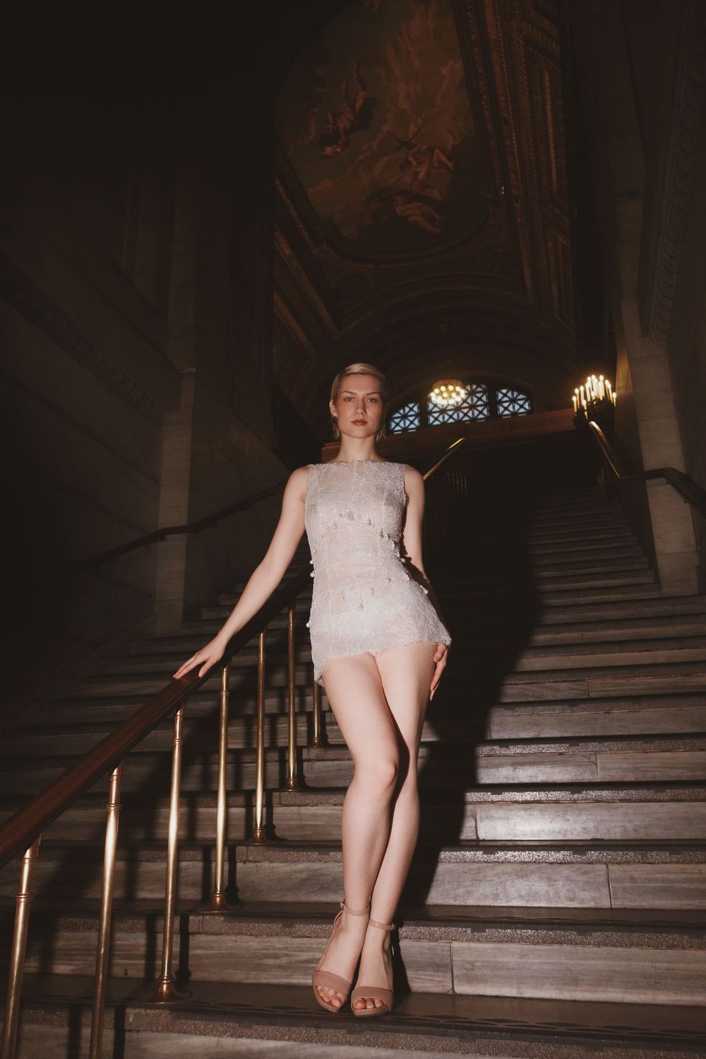 A sequence of photos showing someone walking down dark ornate staircase in an elegant white dress.