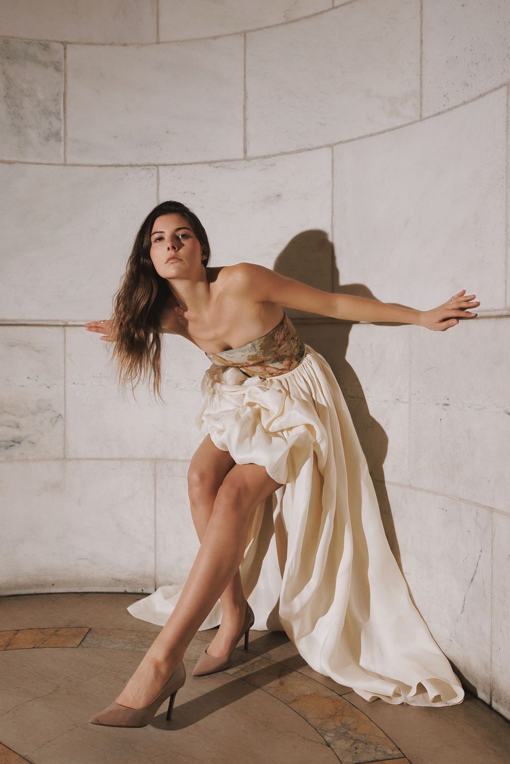Artistic dance performance showcasing flowing cream-colored costumes against concrete walls.
