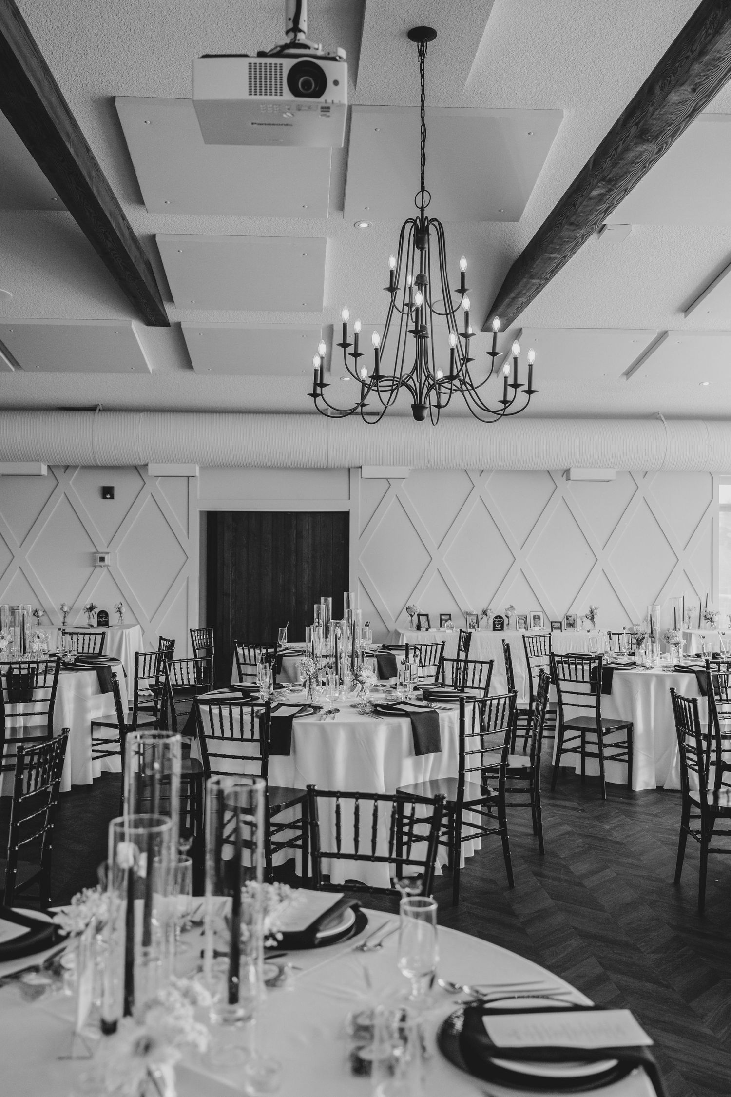Black and white photos of an elegant wedding reception venue with chandeliers, tables and chairs in a rustic-chic space.