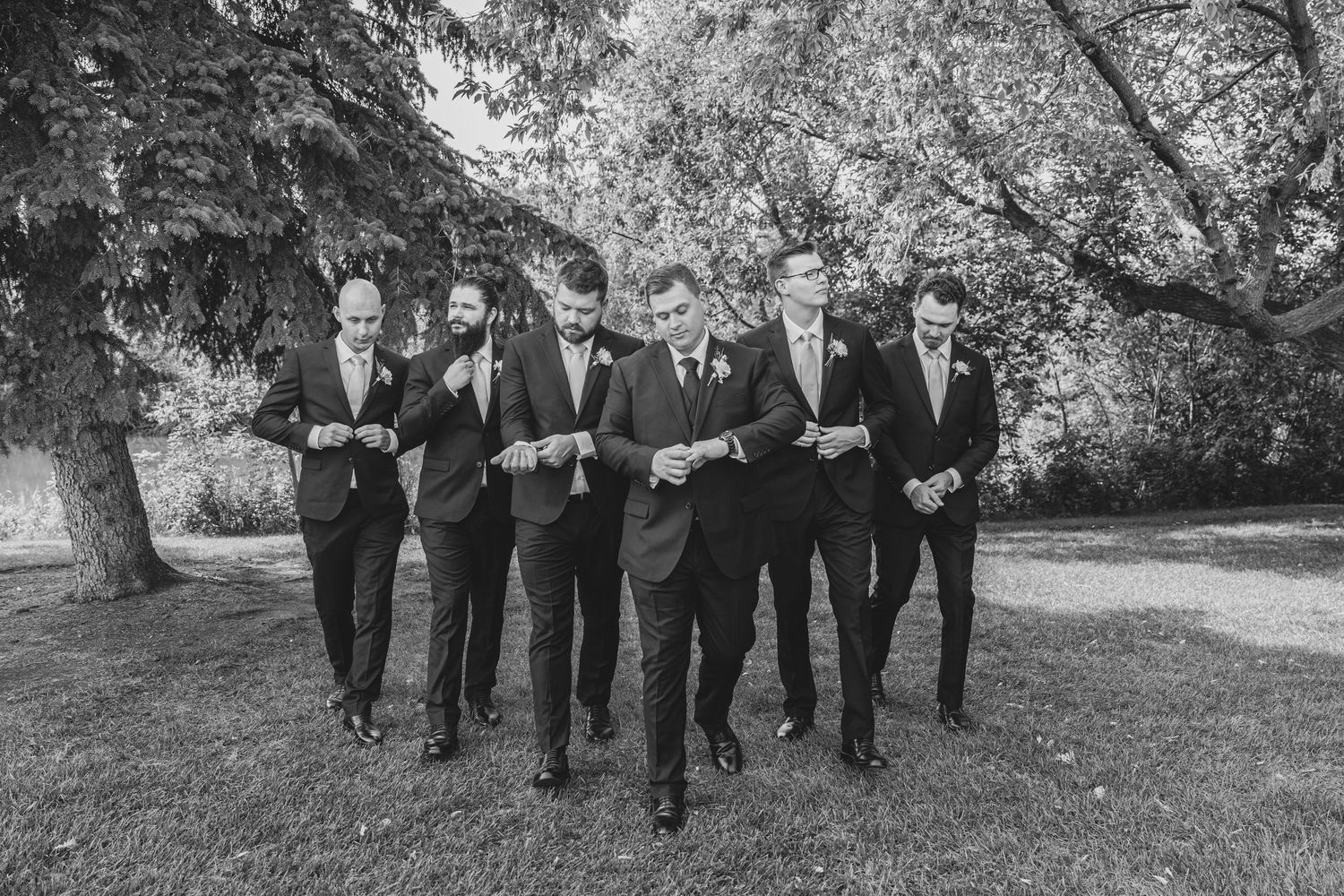 A wedding party makes their way through a scenic garden path in formal black attire.