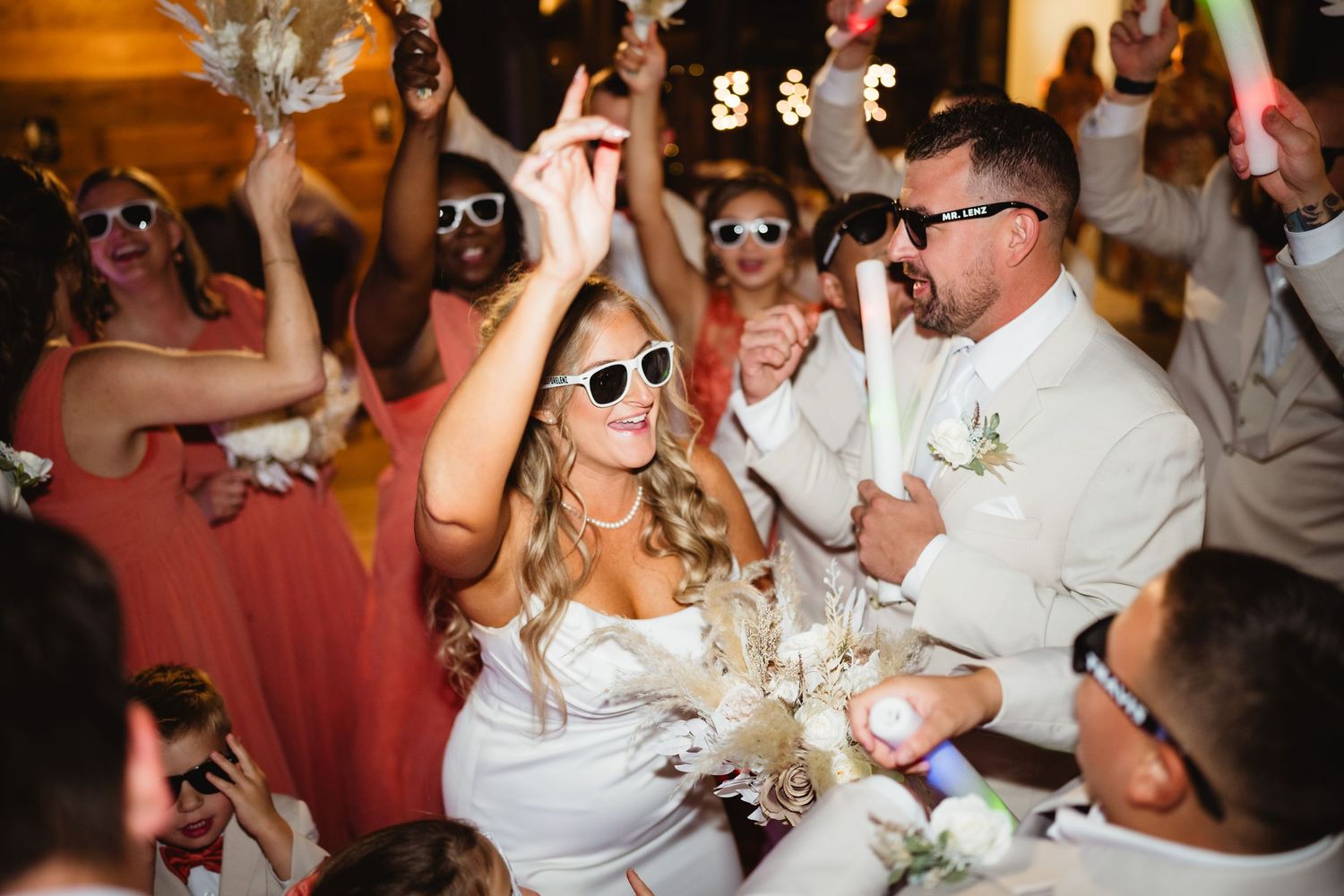 Wedding guests on the dance floor celebrate with raised arms and energetic movements during a reception party.