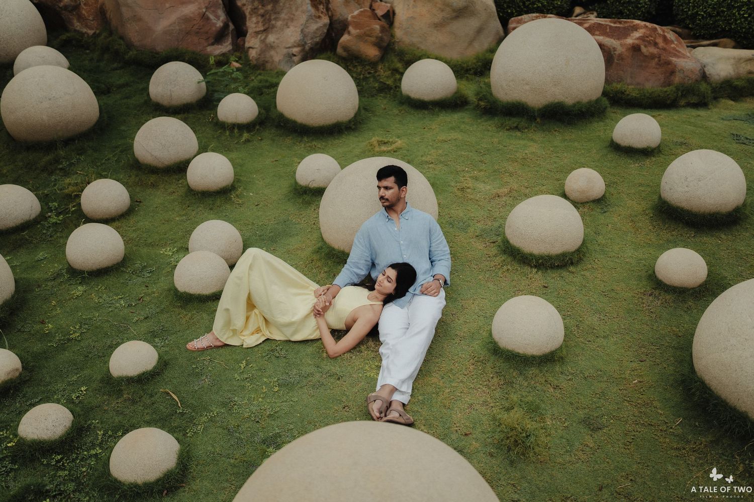 A romantic photoshoot in a garden setting with round white sculptural elements scattered on the grass.
