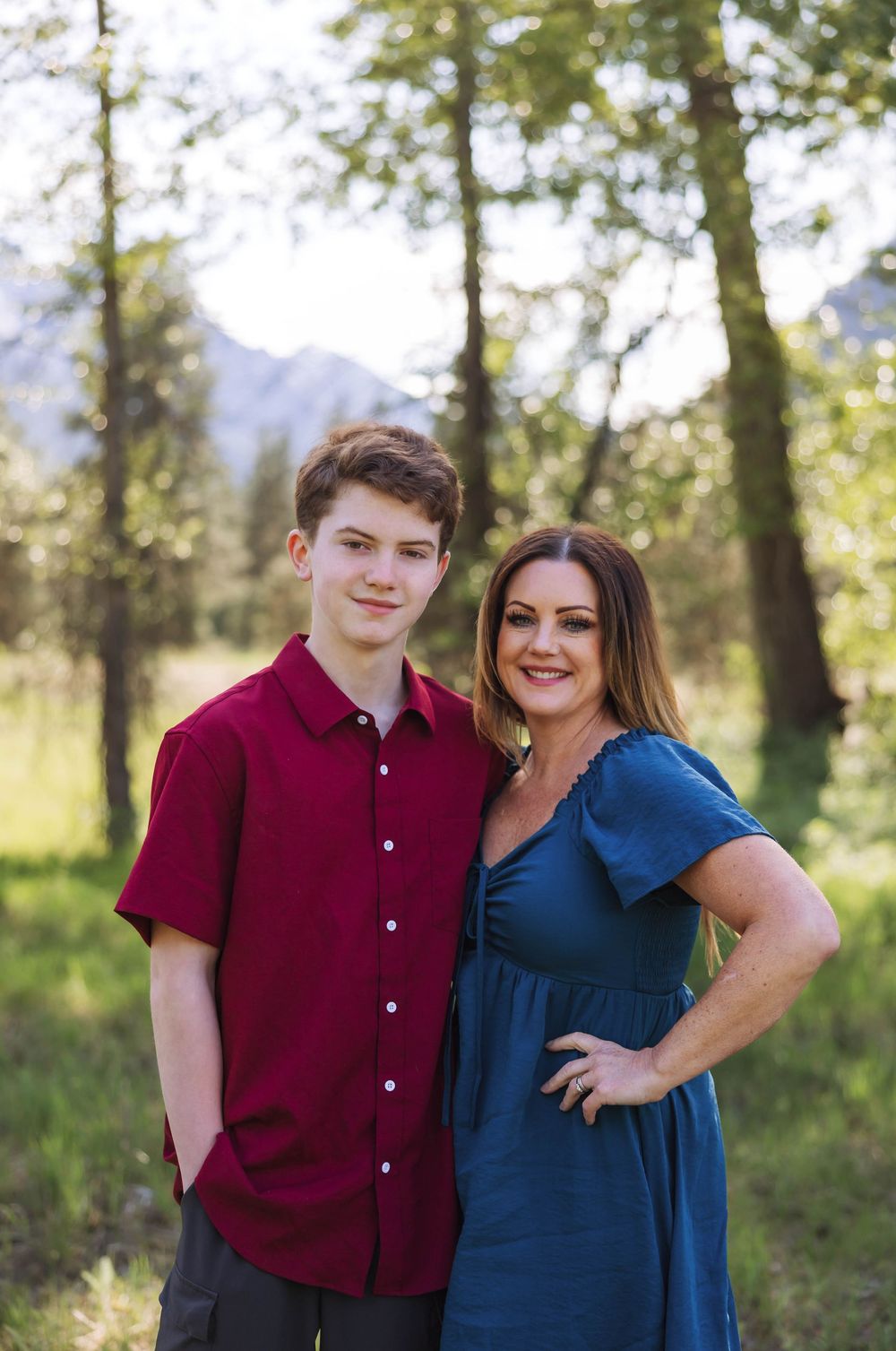 Two people pose together in burgundy and blue outfits during an outdoor photo shoot.