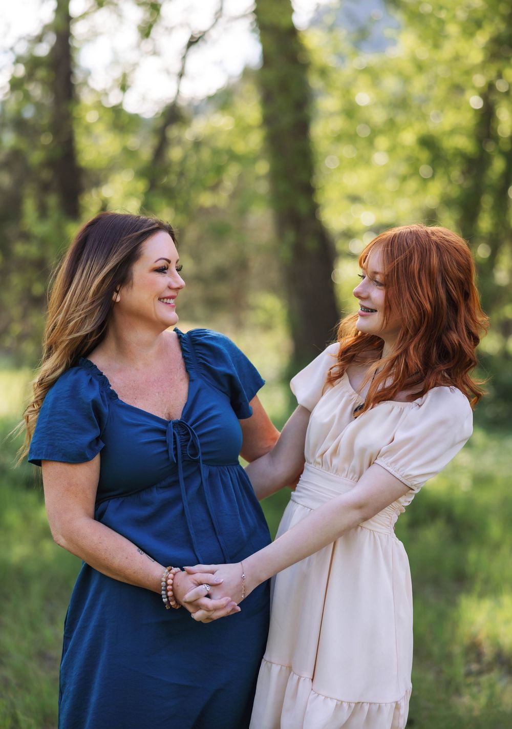 Two people in blue and cream outfits share a joyful moment outdoors.