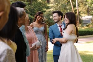 Wedding guests share joyful moments while mingling and socializing outdoors in a sunlit garden setting.