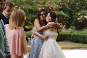 Joyful wedding celebration captured through candid moments and hugs in an outdoor garden setting.