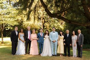 Wedding party poses for formal portraits in a lush garden setting under golden afternoon sunlight.