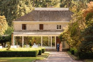 Beautiful autumn landscaping with colorful trees surrounds a charming ranch style home with white trim and brick facade.