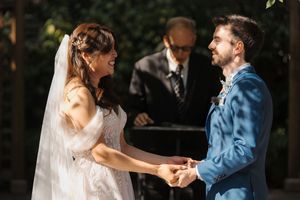 Bride and groom dance together at an outdoor wedding celebration surrounded by guests.