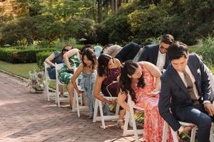 A group sits together on a park bench observing something on the ground in a garden setting.