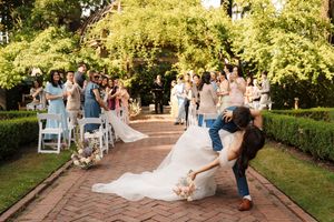 Wedding party captures candid moments during outdoor photo session in lush garden setting.