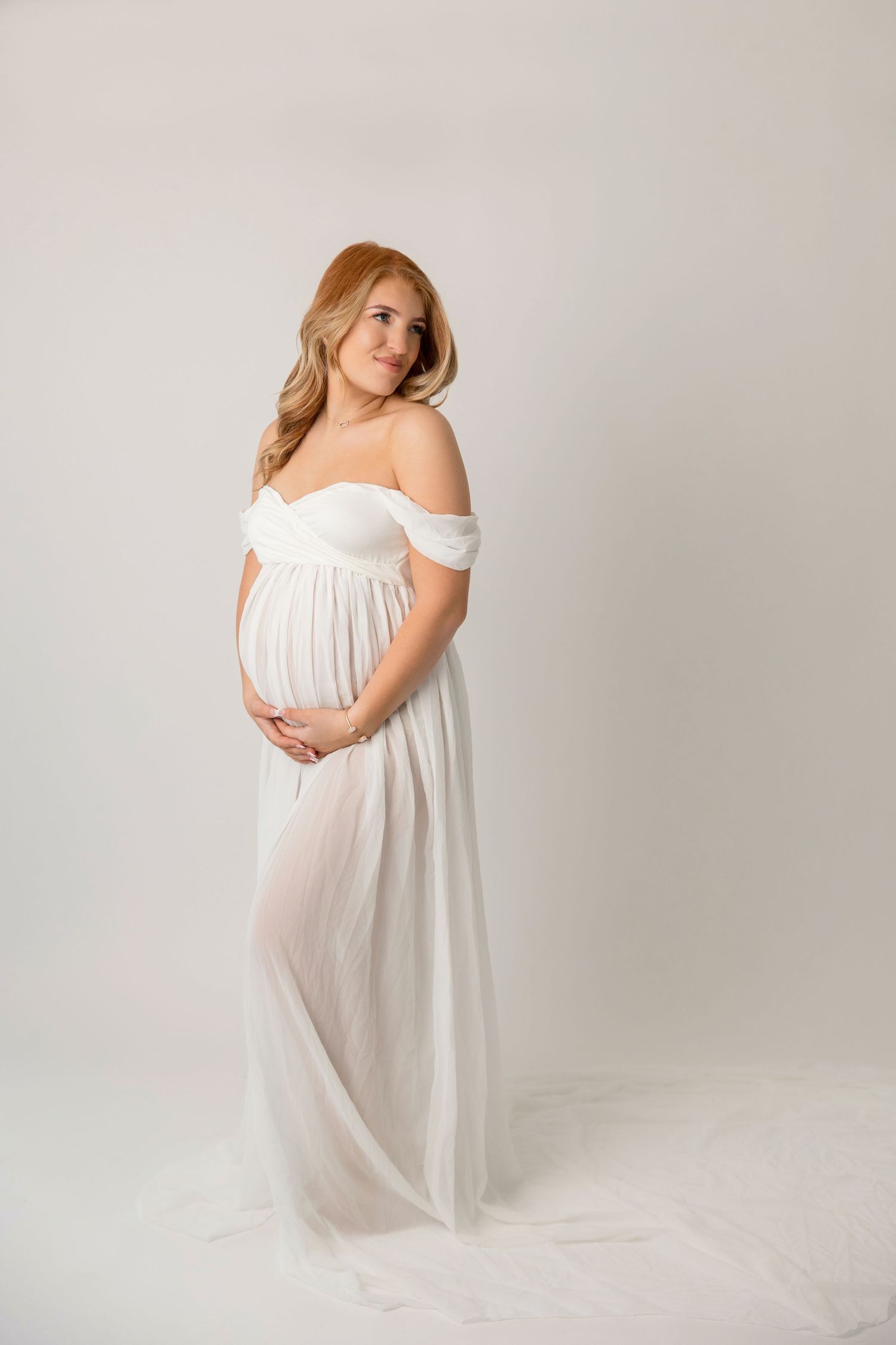 Ethereal maternity photos featuring person in flowing white dress against neutral background.