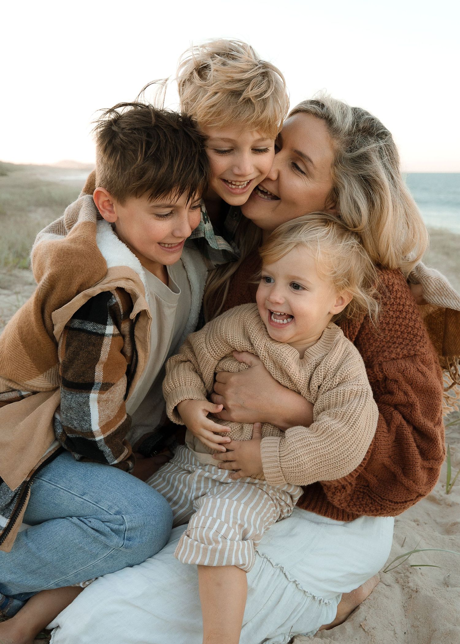 Family sharing playful cuddles and laughter while sitting together at the beach.
