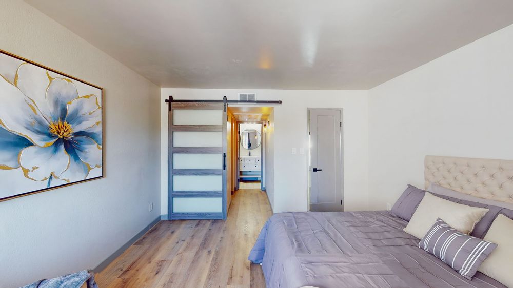 Panoramic view of a bedroom with floral artwork and modern furnishings.