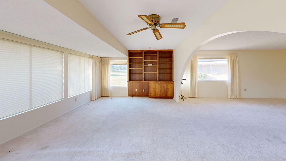 Spacious room interior with ceiling fan and carpeted flooring in neutral tones.