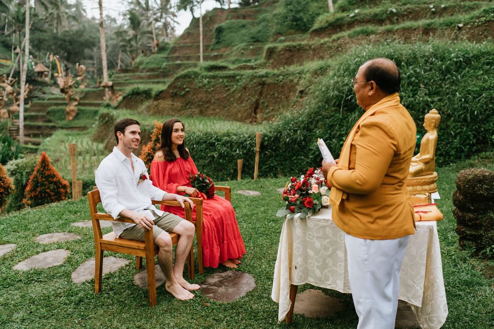 Traditional ceremony setup with guests and officiant in a tropical garden setting with rice terraces.