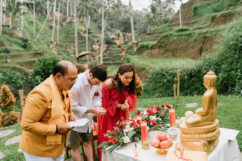 Intimate outdoor ceremony with decorative table setting and golden Buddha statue among rice terraces.