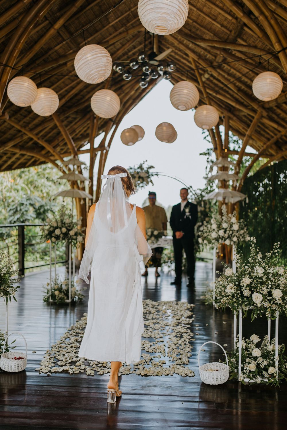 Rustic bamboo wedding venue decorated with white paper lanterns and floral arrangements.