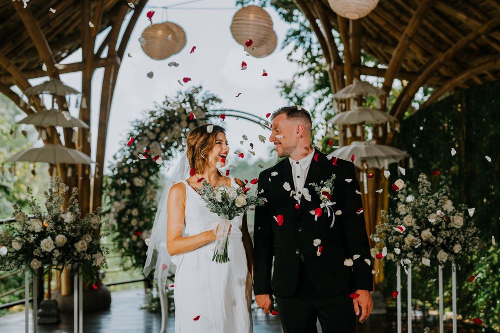 Wedding ceremony in a rustic outdoor pavilion decorated with white lanterns and floral arrangements.