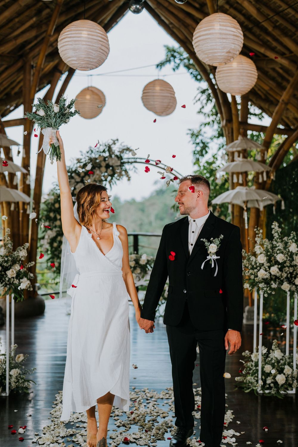 Joyful wedding celebration with paper lanterns and rose petals in an outdoor pavilion.