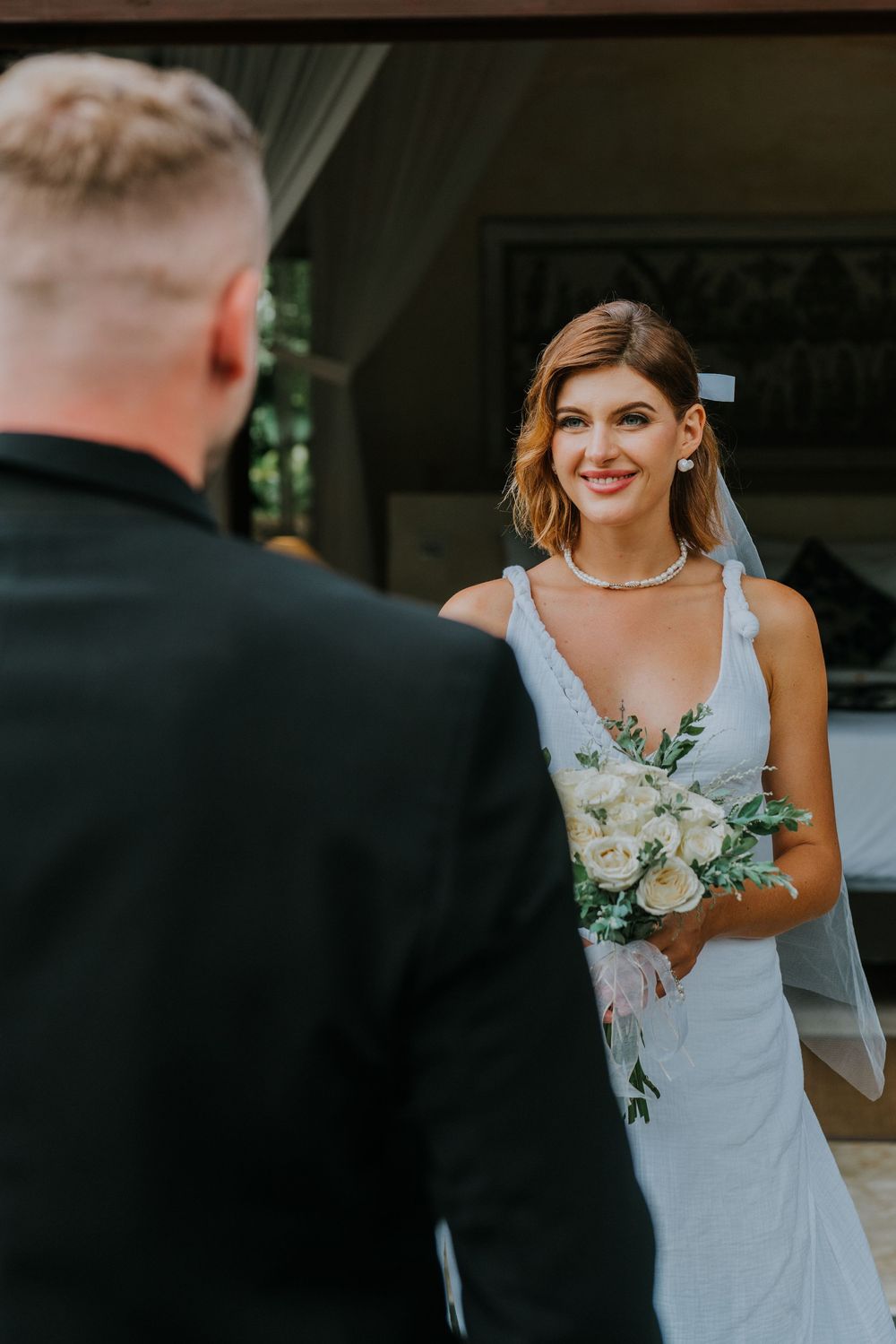 Intimate wedding moment captured under a decorated wooden pavilion.