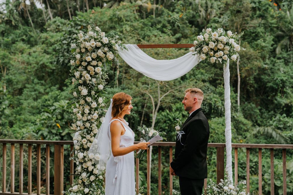 Elegant outdoor wedding ceremony setup with white roses and draped fabric.