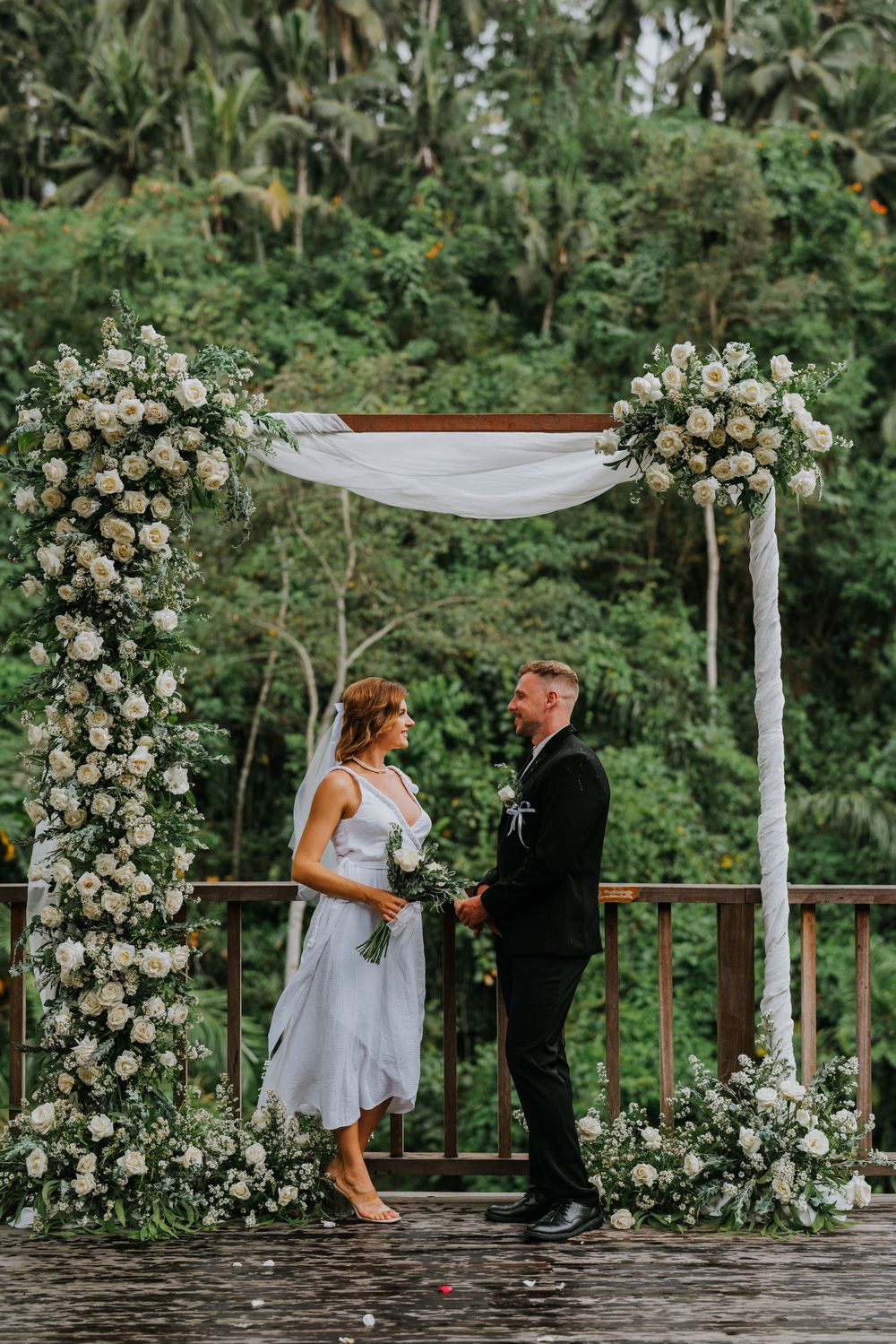 Wedding ceremony space with lush greenery backdrop and white floral arrangements.