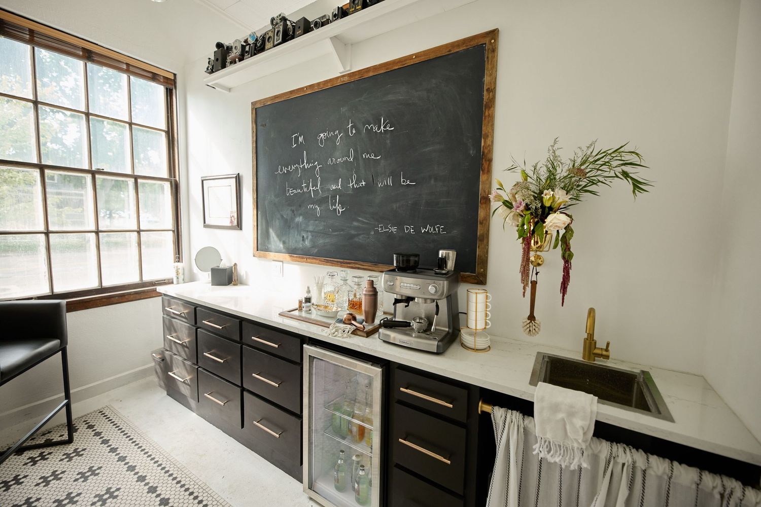 Modern kitchen with black chalkboard wall, wooden countertops, and large windows.