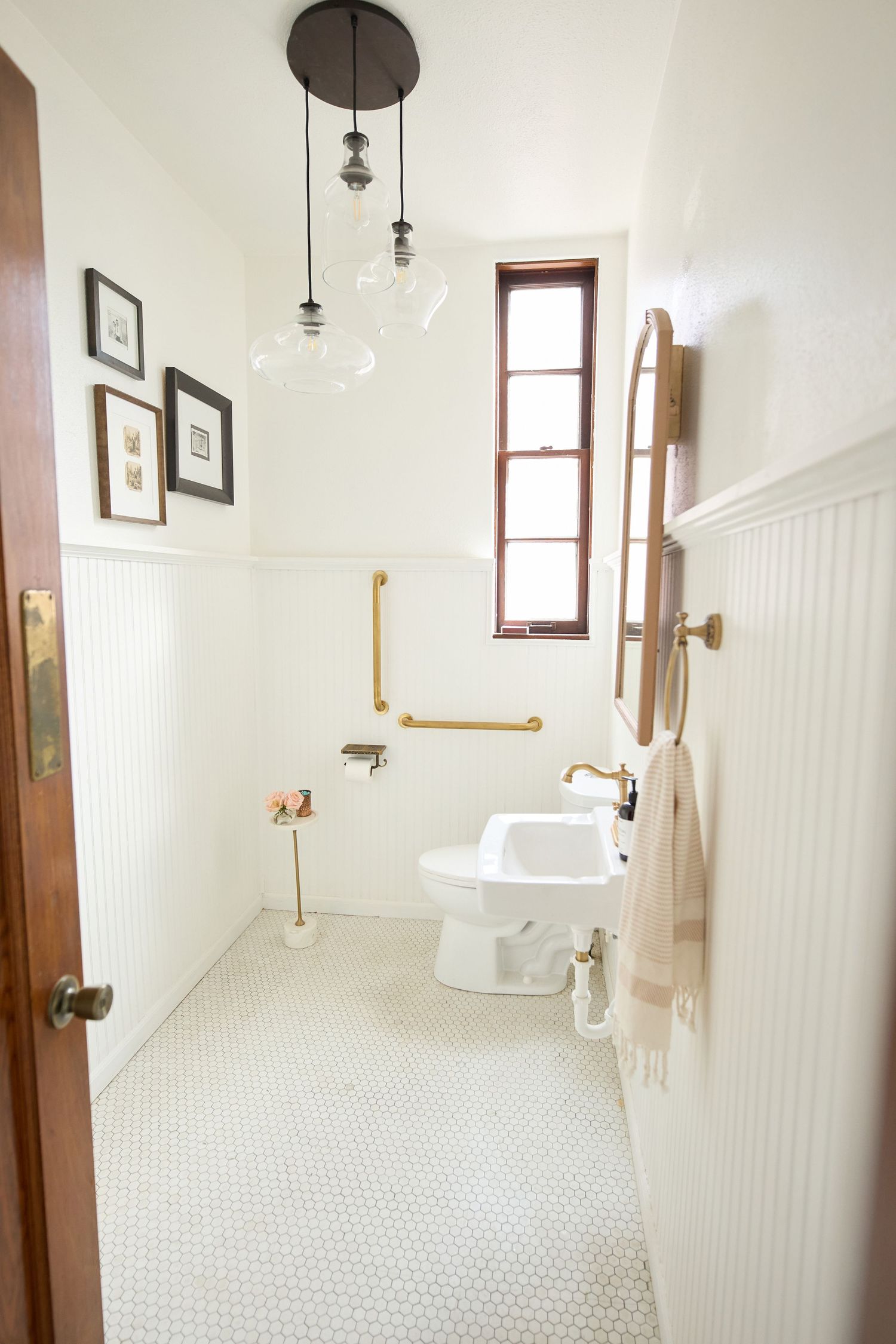 Clean white bathroom with wainscoting, pendant lights, and vintage-style fixtures.