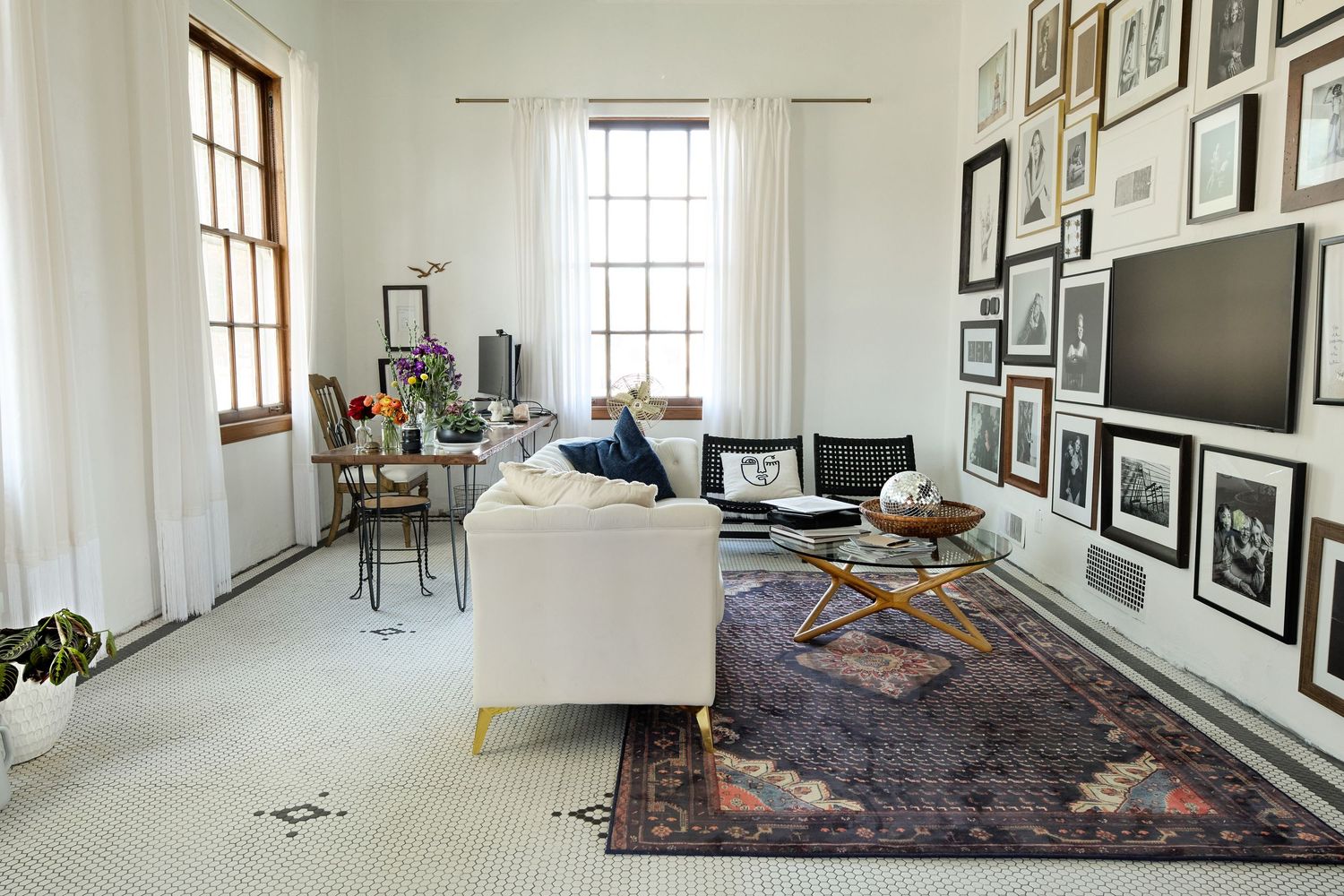 Modern studio space with white walls featuring framed artwork and large windows letting in natural light.