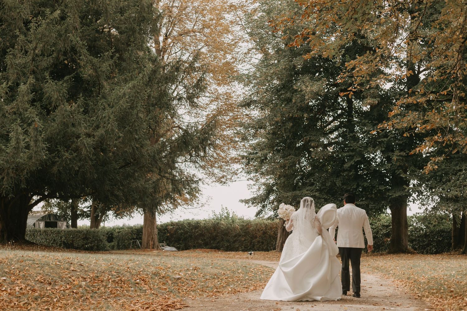 Autumn wedding scene with fallen leaves on the ground and tall trees creating a natural backdrop.