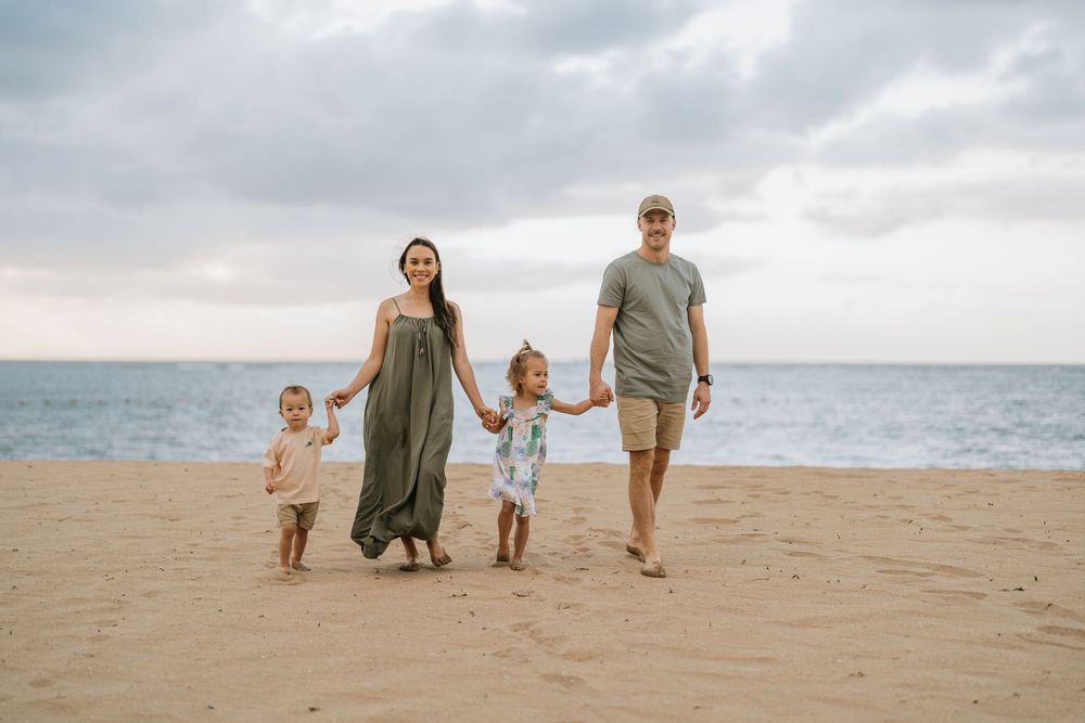 A family walking together on a sandy beach during sunset with ocean views.