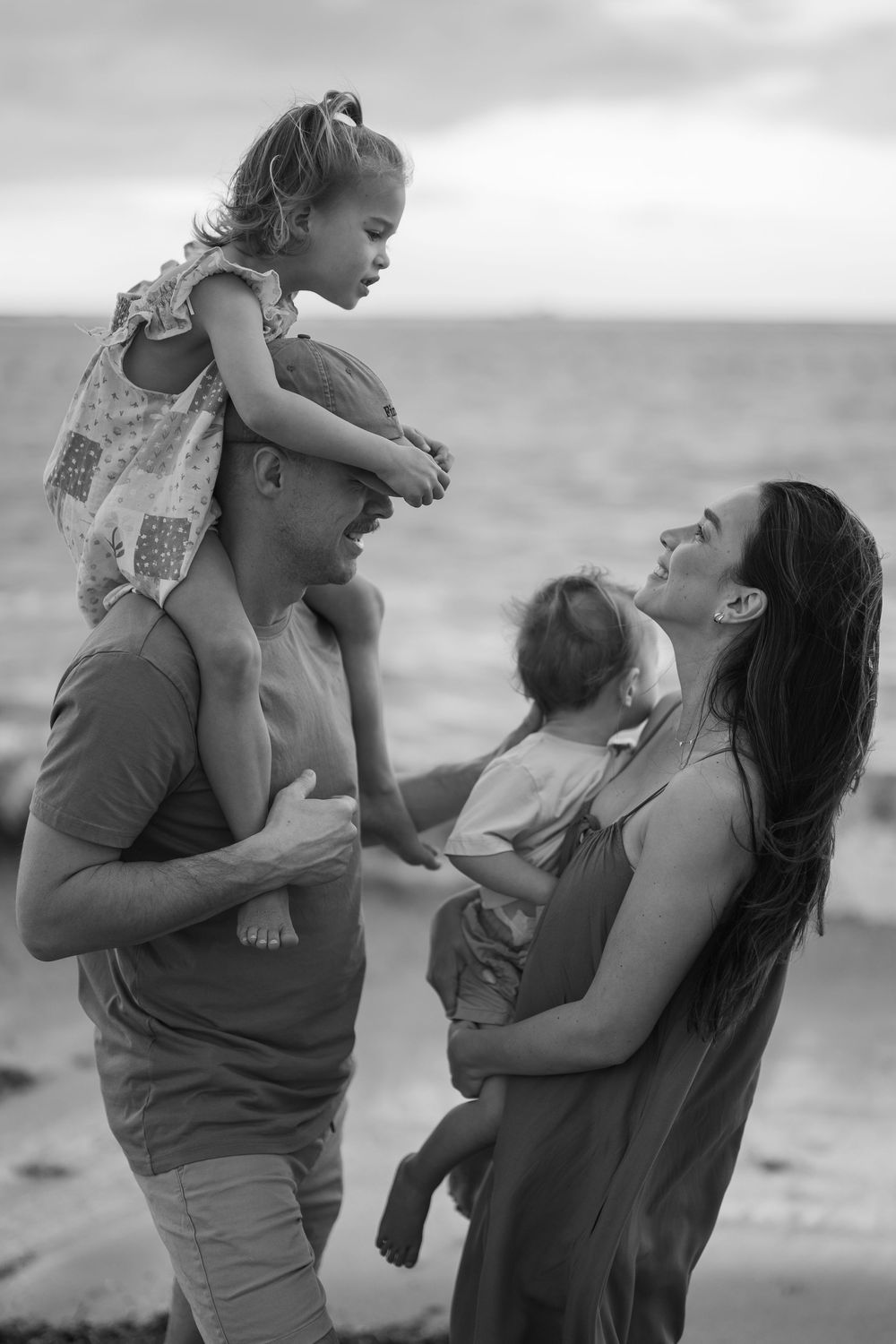 Candid moments of family affection captured on a beach at sunset.