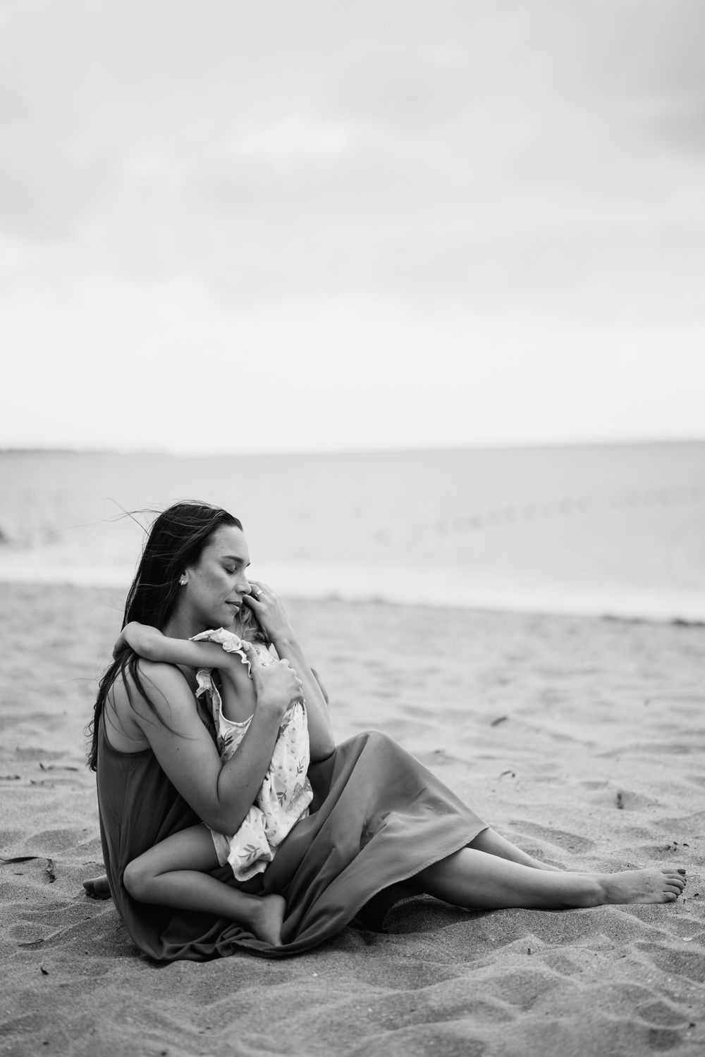 Black and white photos of someone resting peacefully on sandy beach.