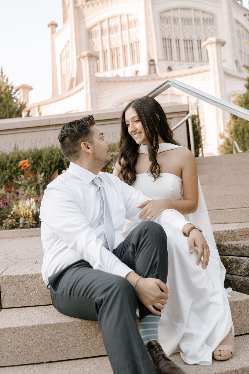 Couple sitting together on stone steps outside an elegant building sharing a romantic moment together.