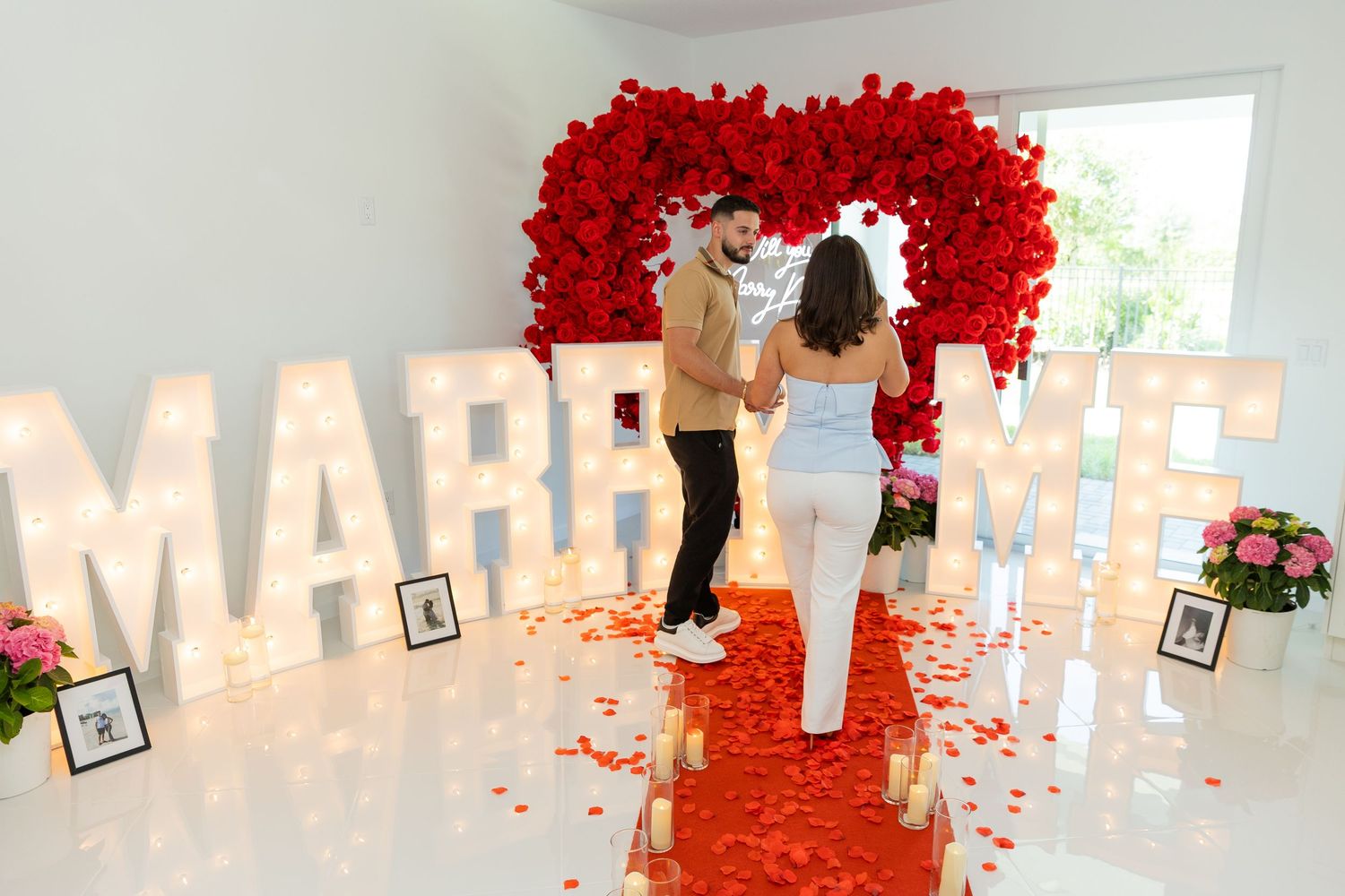 A row of bold red paper carnations elegantly adorn the wall with white lettering visible in the background.